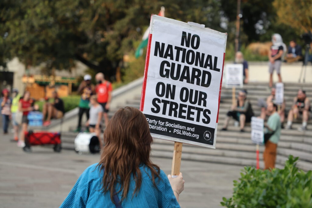 A demonstrator holds a sign protesting President Trump's proposed plans to deploy federal troops to New Orleans on Tuesday, September 16, 2025.