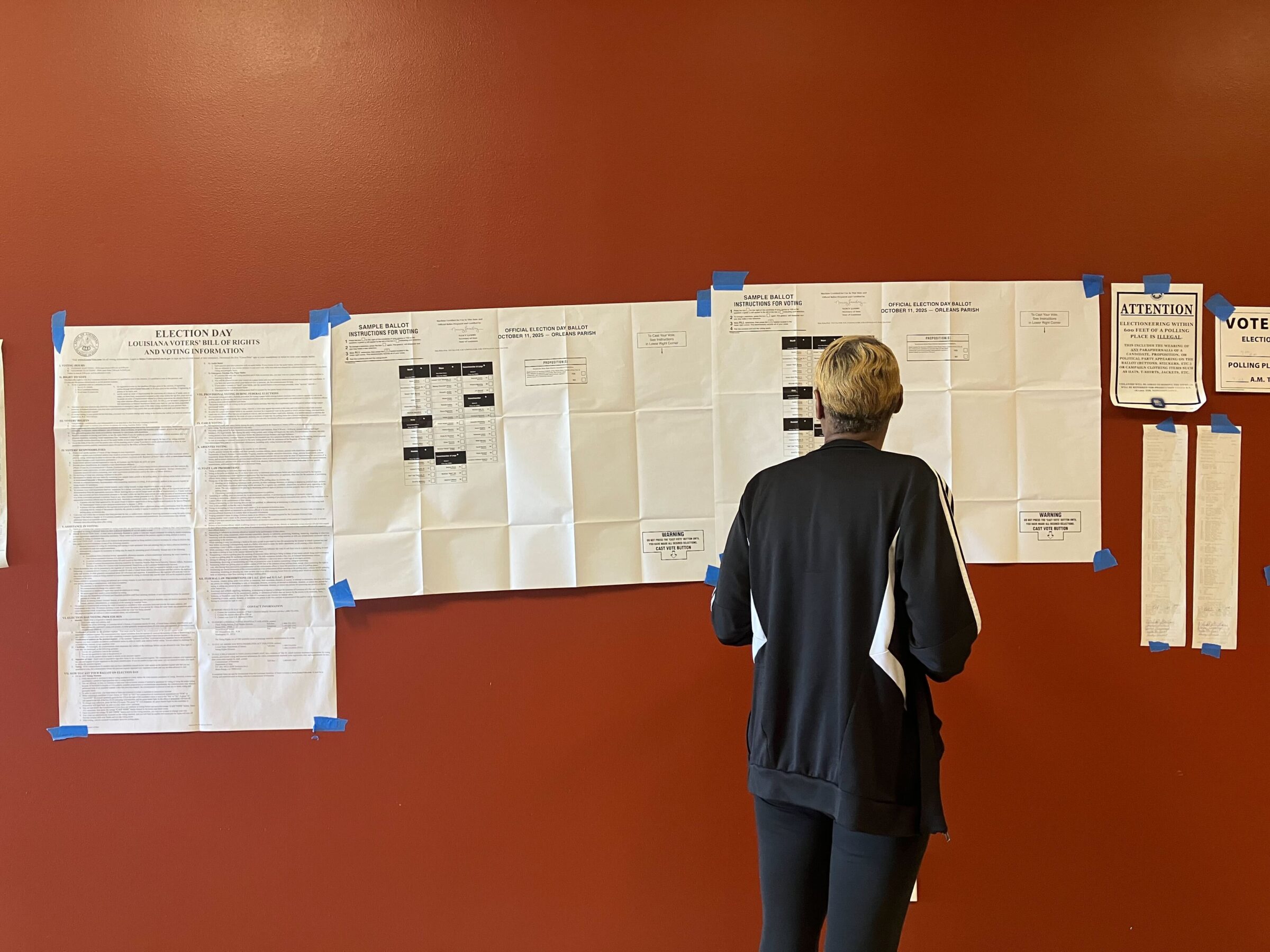A voter inspects a sample ballot outside the polls at the Household of Faith church in New Orleans East on Saturday, Oct. 11, 2025.